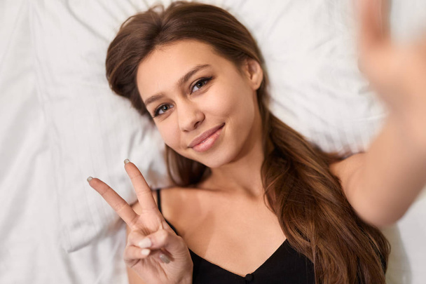 Jonge vrouw die selfie op bed - Foto, afbeelding