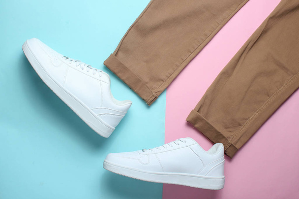 Pantalones beige, zapatillas blancas sobre fondo pastel de colores, look a la moda, vista superior, minimalismo
 - Foto, Imagen