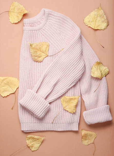 Fashionable sweater among the fallen yellowed leaves on  brown background. Autumn wardrobe. top view - Photo, Image