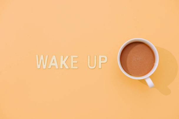 WAKE UP text with a cup of coffee with shadow on pink background. - Photo, image