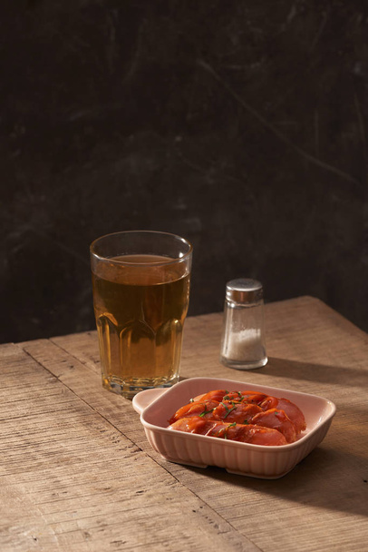 Glass of delicious beer with grilled sausages on wooden table - Foto, immagini