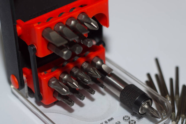 Bits holder in box and many tool bits on white background. Close-up view. Red element in plastic box. - Foto, Imagen
