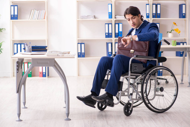 Молодий чоловік працівник в інвалідному візку працює в офісі
  - Фото, зображення