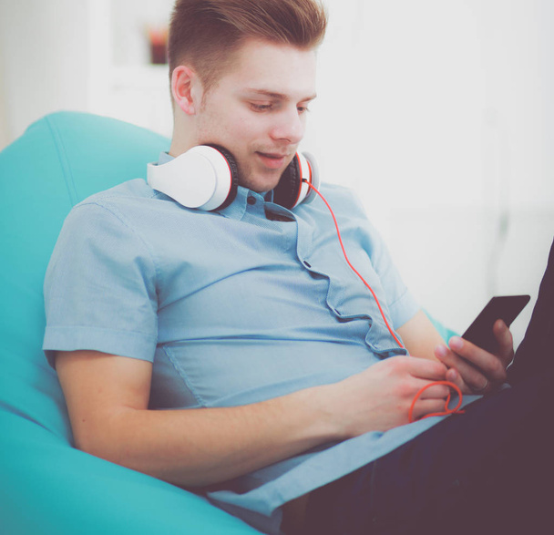 A young handsome man on the couch listening to music - Foto, imagen