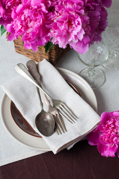 de instelling van de tabel met roze pioenrozen, vintage bestek en bruin tabel - Foto, afbeelding