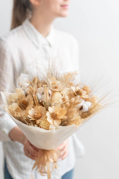 beautiful bouquet of mixed dried flowers in woman hand. the work of the florist at a flower shop. Delicate Pastel tones color - Foto, Imagen