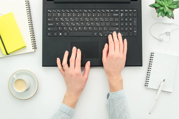 Topview της εργασίας γυναίκα δημιουργικό σχεδιαστή δακτυλογράφησης στο πληκτρολόγιο φορητού υπολογιστή. Flat Lay με καφέ κούπα και κενές εγκοπές - Φωτογραφία, εικόνα