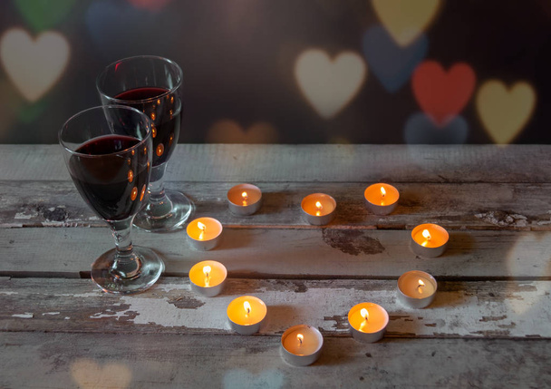 Γυαλιά κόκκινου κρασιού με κεριά σε παλαιωμένο ξύλινο τραπέζι. Επιλεκτική εστίαση. - Φωτογραφία, εικόνα
