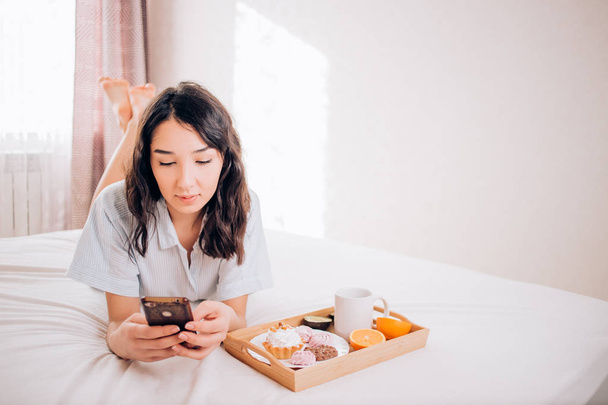 Young woman eating healthy breakfast in bed - Foto, afbeelding