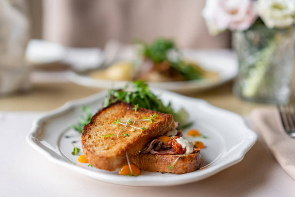 Французские булочки с тостами, сэндвич с пастрами и сушеными помидорами. Легкий завтрак, свежая теплая выпечка на столе в ресторане
 - Фото, изображение