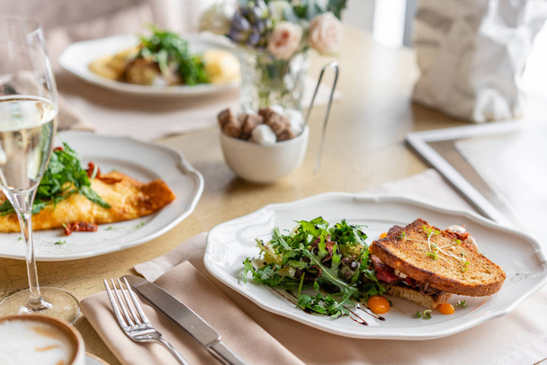 フレンチトーストブリオッシュ、パストラミとドライトマトのサンドイッチ。明るい朝の朝食、レストランのテーブルの新鮮な温かいペストリー - 写真・画像