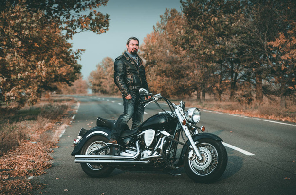 Motociclista elegante posando com motocicleta na estrada
. - Foto, Imagem