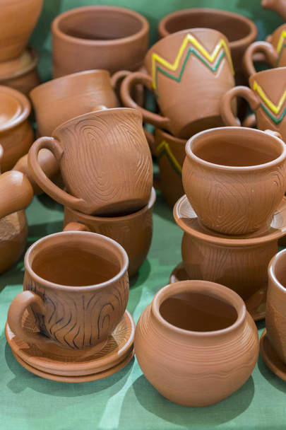 viele traditionelle ukrainische handgemachte Tonkeramik-Produktion. Braune Keramik. Teller und Tassen aus Ton. vertikales Foto. - Foto, Bild