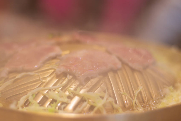 Χοιρινό σε φέτες που έχει ψητό σε καμπυλωτό μπρούτζινο τηγάνι - Φωτογραφία, εικόνα