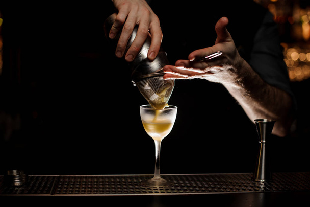 Чоловік бармен виливає смачний коктейль зі сталевого шейкера через сито
 - Фото, зображення