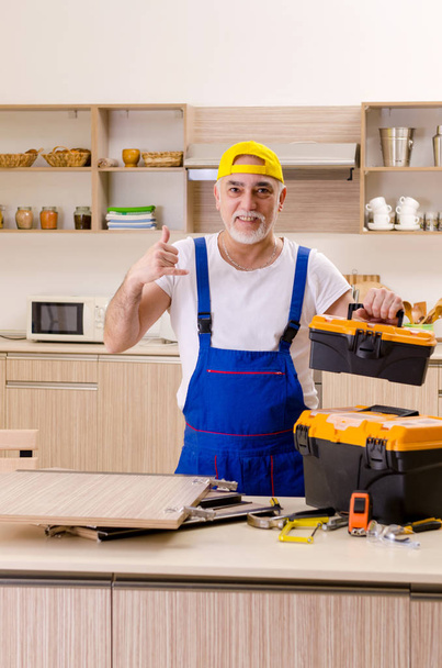 Aged contractor repairman working in the kitchen  - Foto, Imagem