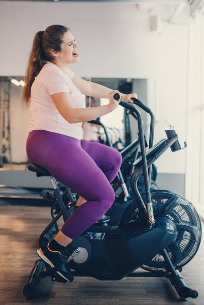 Fat woman intensely exercising on stationary bike - Foto, Bild