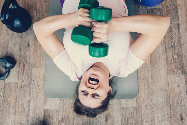 Fat female does very hard exercise in fitness club - Photo, Image
