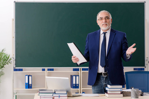 Aged male teacher in front of chalkboard  - Foto, afbeelding
