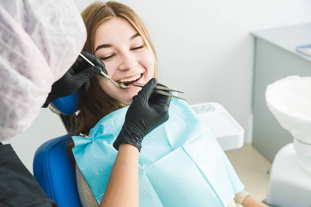 Dental clinic. Reception, examination of the patient. Teeth care. Young girl undergoes a dental examination by a dentist - Valokuva, kuva