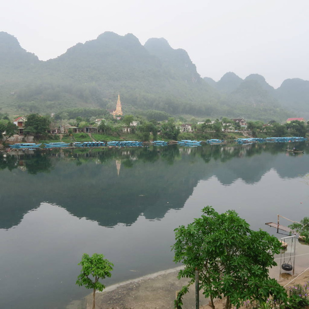 Bela paisagem fluvial no Parque Nacional "Phong Nha" e os barcos levam os turistas para a caverna, março 2019, Vietnã Central
 - Foto, Imagem