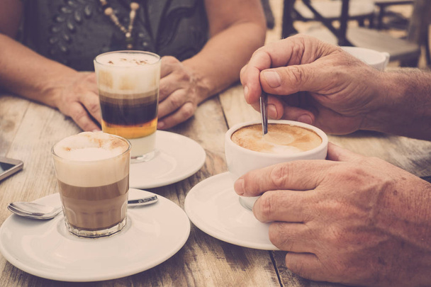 Close-up van de handen met koffiekopjes in een cafe bar genieten van cappuccino voor een smakelijk ontbijt in de ochtend  - Foto, afbeelding