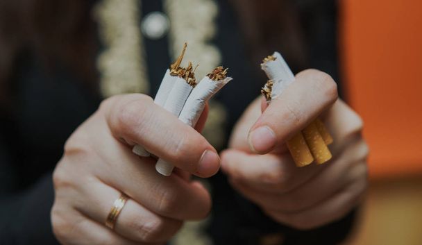 Женщина, которая разбивает сигарету и бросает курить. Крупный план кукурузницы, делящей сигарету для идеи бросить курить
 - Фото, изображение