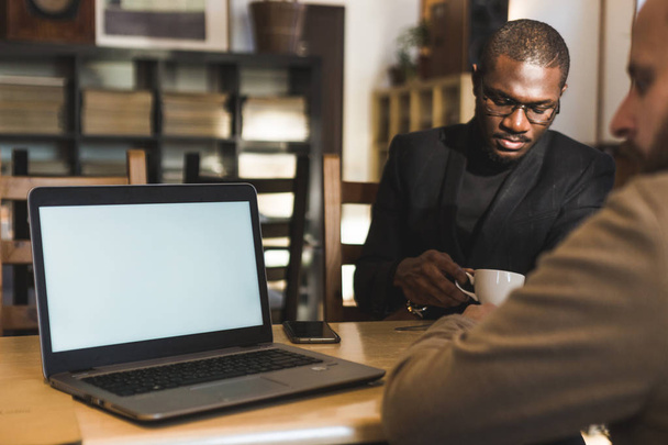 Multicultural african and caucasian businessmen negotiate in a cafe. - Fotó, kép