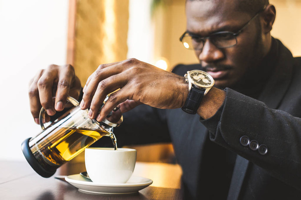 Young handsome dark-skinned businessman in a cafe with a cup of tea. - Фото, зображення