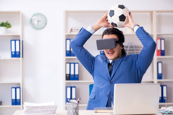 Young handsome businessman playing soccer with virtual glasses  - Photo, image