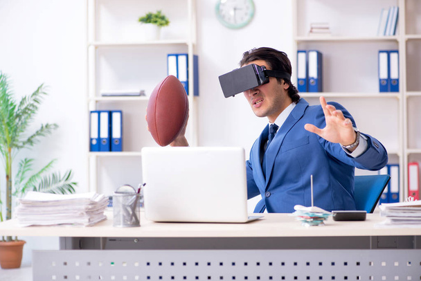 Молодой привлекательный бизнесмен играет в регби с виртуальными очками
 - Фото, изображение