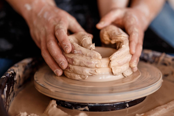 happy family on a creative joint vacation. romantic couple in love working together on potter wheel and sculpting clay pot - Фото, изображение