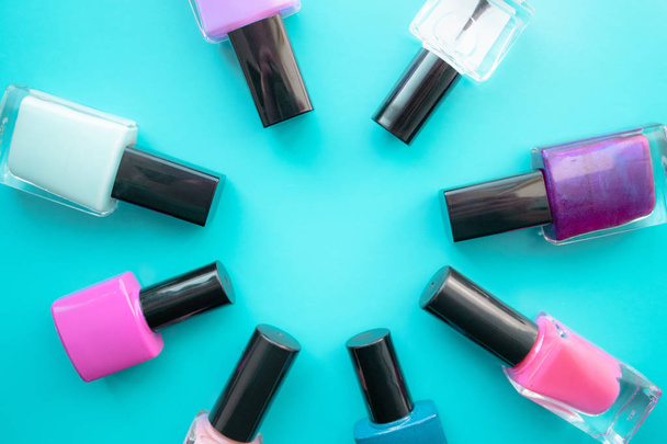Bottles of nail polish. A group of bright nail polishes on a green background. With empty space in the middle. - Foto, Bild