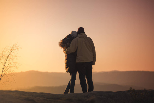 Egy férfi és egy nő sziluettek a hegycsúcson napkelte. - Fotó, kép