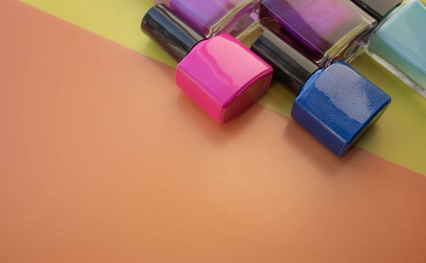 Bottles of nail polish. A group of bright nail polishes on a colored, yellow background. With empty space on the left. - Photo, Image