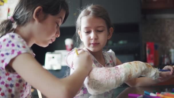 Kinder malen einen gebrochenen Arm in einen Verband. Schwester versucht, eine kranke Schwester aufzuheitern und aufzuhängen. - Filmmaterial, Video