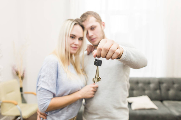A lovely young couple holds in front of them the keys to their new apartment. - Fotó, kép