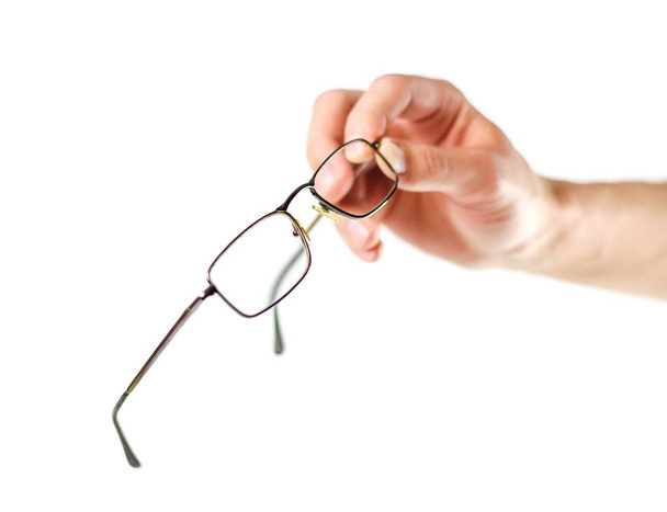 Χέρια κρατώντας γυαλιά για τη διόρθωση της όρασης. Κοντινό. Απομονωμένο - Φωτογραφία, εικόνα