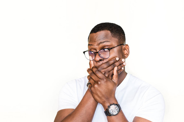 Surprised handsome African American man in glasses covers mouth in shock. - Foto, immagini