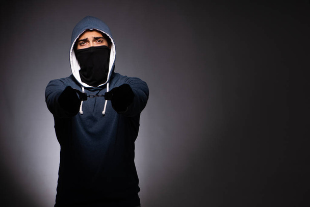 Молодой бандит в капюшоне на сером фоне
  - Фото, изображение