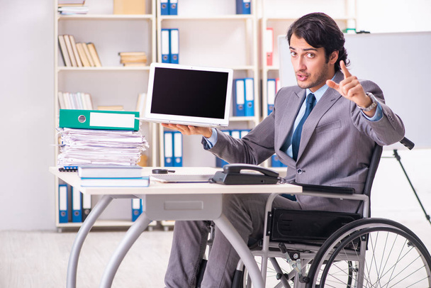 Giovane bel dipendente in sedia a rotelle in ufficio
  - Foto, immagini