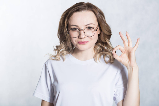 Handsome young woman in glasses shows ok sign. Body language concept. - Φωτογραφία, εικόνα