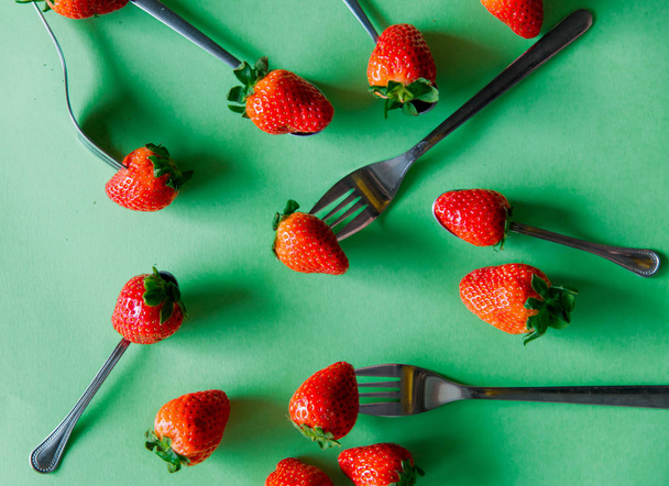 Spring season strawberry and forks on green background - Foto, Bild