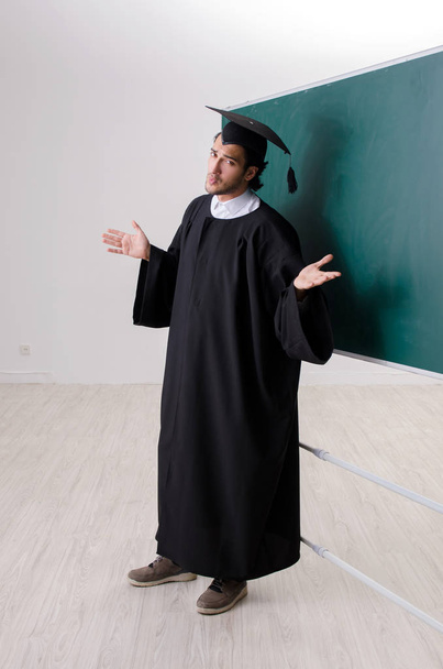 Graduate student in front of green board  - Фото, зображення