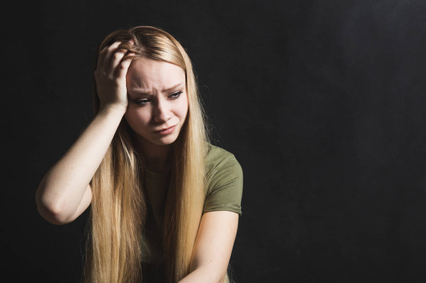 Sad young woman going to cry in a black background - Photo, image