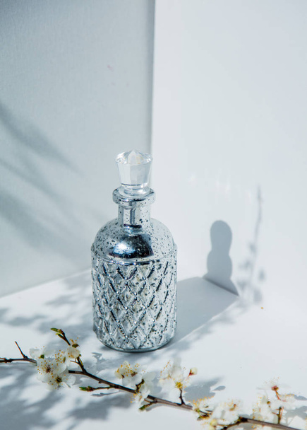 Butelka perfum i Wiśniowa gałąź z kwiatami - Zdjęcie, obraz