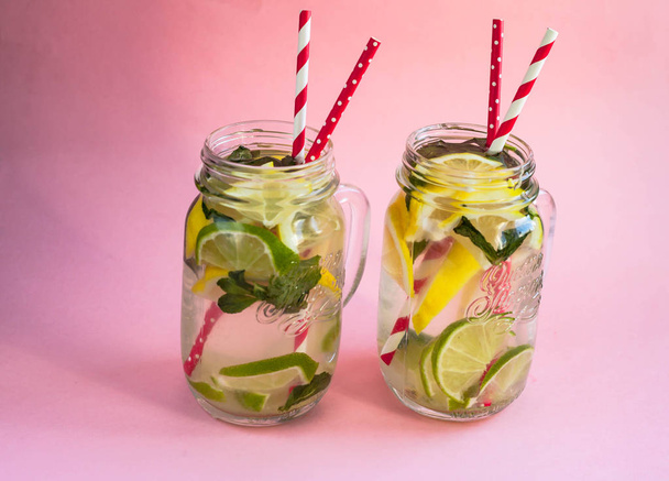 Two jars of tasty cold lemonade on a pink background - Φωτογραφία, εικόνα