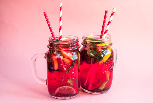 Two jars of tasty cold lemonade on a pink background. - Фото, зображення