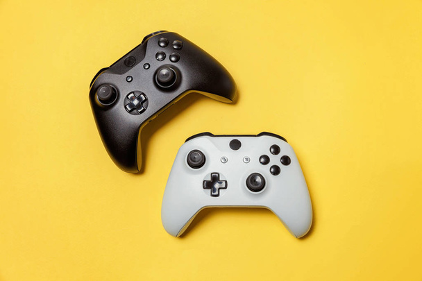 黄色の背景に白と黒の2つのジョイスティック。コンピュータゲーム競技大会ビデオゲーム制御対決コンセプト - 写真・画像