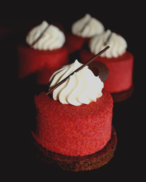 Красные текстурные десерты с кремовым верхом и шоколадными украшениями
 - Фото, изображение